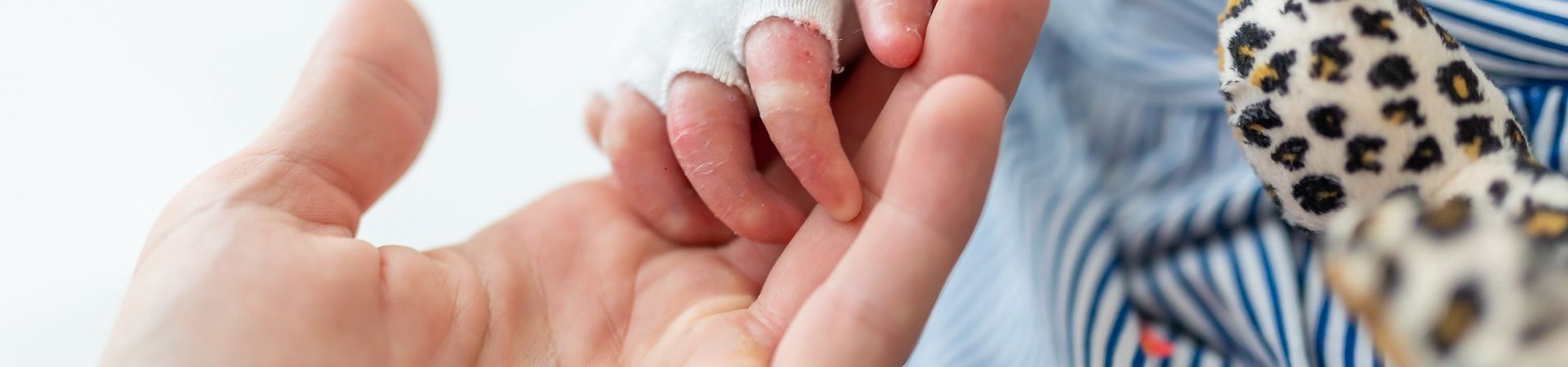 Hand holding a bandaged child's hand close-up
