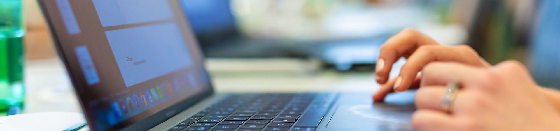 Close-up of laptop from the side with hands on the touchpad