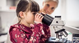 Small EB child with red dress looking into microscope