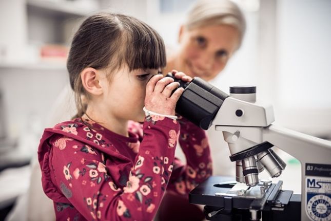 EB child looking into a microscope in an EB lab